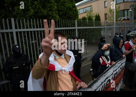 Warsaw, Warsaw, Poland. 25th May, 2021. A man wrapped in a historical Belarusian flag gestures a victory sign in front of the embassy of Belarus on May 25, 2021 in Warsaw, Poland. Around a hundred of people gathered next to the Belarusian embassy to demand freedom for political prisoners detained in Belarus after the arrest of Roman Protasevich, a prominent Belarusian opposition Journalist. Credit: Aleksander Kalka/ZUMA Wire/Alamy Live News Stock Photo