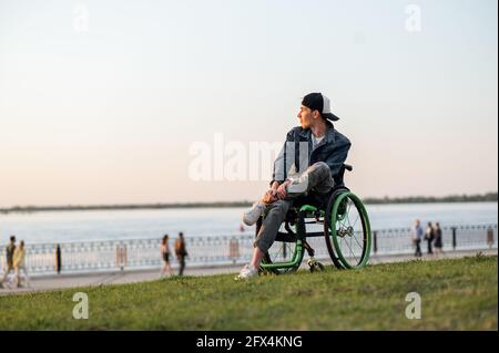 a young man in a wheelchair, walking around the city, enjoying the sunset Stock Photo