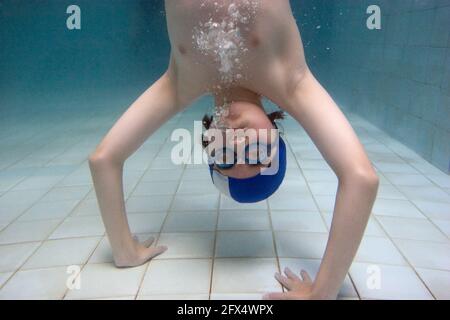 Young boy in handstand poses in swimming pool Stock Photo
