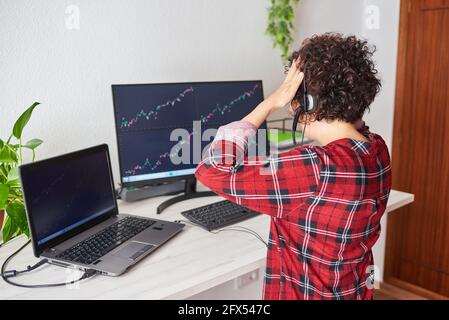 An unrecognizable woman who is a trader puts her hands on her head for a bad investment Stock Photo