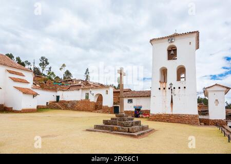 White church and stone cross in the town square of Chinchero, a rustic Andean village in the Sacred Valley, Urubamba, Cusco Region, Peru Stock Photo