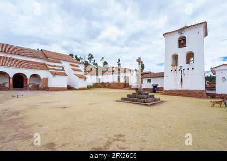 White church and stone cross in the town square of Chinchero, a rustic Andean village in the Sacred Valley, Urubamba, Cusco Region, Peru Stock Photo