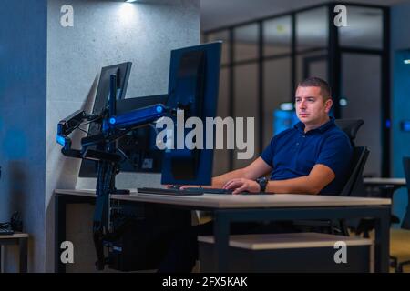Group of Security data center operators (administrators) working in a group at a CCTV monitoring room while looking at multiple monitors ( computer sc Stock Photo