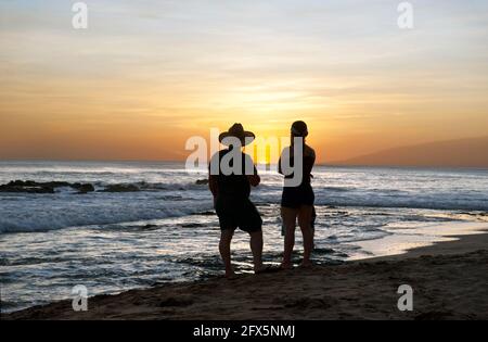 Couple watching the sunset from a beach in Tamarindo, Costa Rica, Central America Stock Photo