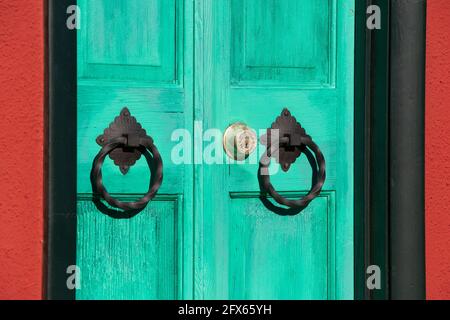 Aquamarine wooden door with ornate door knockers on house exterior  in Barrio Viejo, Tucson's historic old neighborhood Stock Photo