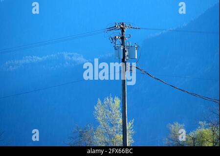 Utility pole with transformers and cables against a mountain background.  British Columbia, Canada. Stock Photo