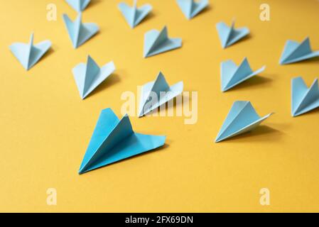 Group of blue paper aeroplane origami on yellow background. Concept of leadership, teamwork and art craft Stock Photo