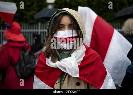 Warsaw, Poland. 25th May, 2021. A young protester wears a face mask in the colors of the forbidden historical Belarusian flag during the protest.Belarusians residents in Poland gathered outside the Embassy of Belarus to protest against the arrest of Roman Protesevich, dissident journalist and the repressions on activists by Aleksander Lukashenko. (Photo by Attila Husejnow/SOPA Images/Sipa USA) Credit: Sipa USA/Alamy Live News Stock Photo