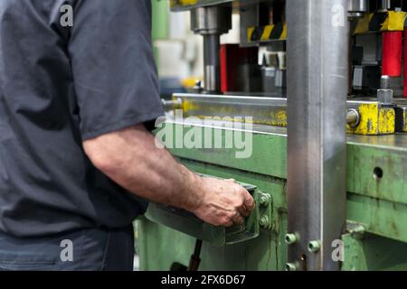 Steel Manufacturing Plant. A Worker is Placing a Piece of Metal Inside the Press. The Press is pushed Down. Metallurgy. Production Process. Close up. High quality photo. Stock Photo