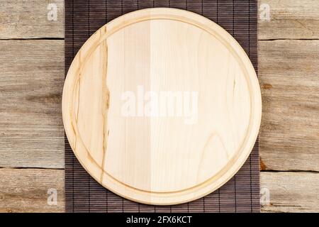 Background with wooden pizza board with bamboo table placemat over grunge rustic background Stock Photo