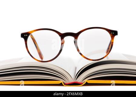 Close-up of opened book with reading glasses isolated on white background, front view Stock Photo