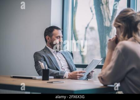 Attentive boss studying document and woman assistant. Stock Photo