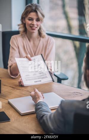 Young woman boss giving documents to man in suit Stock Photo