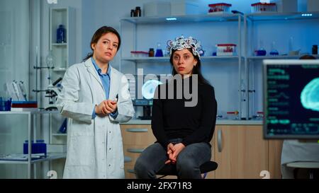 Researcher and patient with eeg headset looking at virtual display with touchscreen, virtual reality using medical inovation in neurological research lab. Scientists working with healthcare simulator Stock Photo