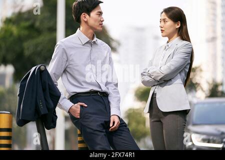 two asian business people chatting on street in downtown of modern city Stock Photo