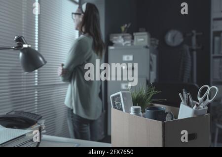 Pensive woman in the office packing her belongings, she has been fired Stock Photo