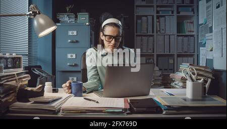 Stressed woman sitting at desk and working with her laptop Stock Photo