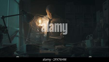 Corporate businessman searching for paperwork in an abandoned office: failure, financial crisis and outdated business concept Stock Photo