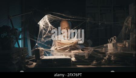 Corporate businessman searching for paperwork in an abandoned office: failure, financial crisis and outdated business concept Stock Photo