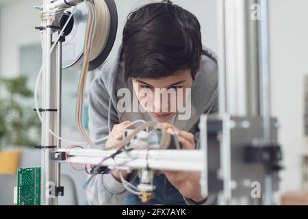 Young smart student using a 3D printer in the lab, engineering and technology concept Stock Photo