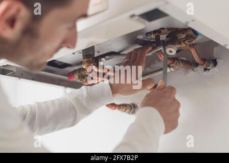 Professional plumber checking a boiler and pipes, he is using a wrench Stock Photo