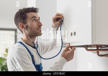 Expert plumber checking the boiler with a stethoscope, boiler servicing concept Stock Photo