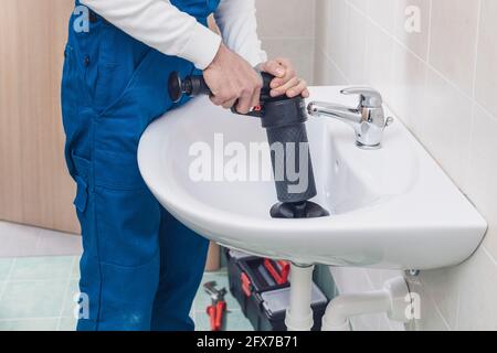 Professional plumber unclogging a sink using an air pump plunger Stock Photo