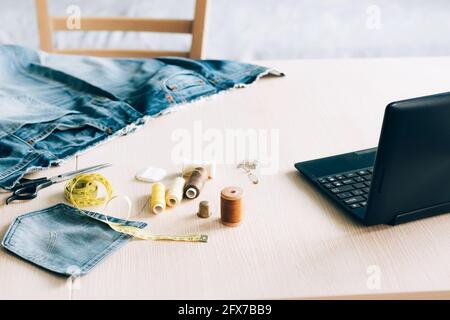 Workplace for online learning and watching a sewing lesson on a laptop. Concept of trendy online learning taking courses at home. Home craft hobby Stock Photo