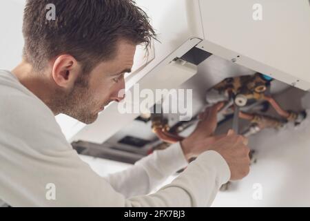 Professional plumber checking a boiler and pipes, he is using a wrench Stock Photo