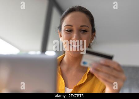 Smiling woman connecting with her laptop and doing online shopping with her credit card Stock Photo