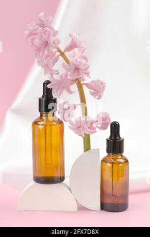 Two brown bottles with a dropper with essential oils or serum with hyacinth flowers. Care and beauty concept