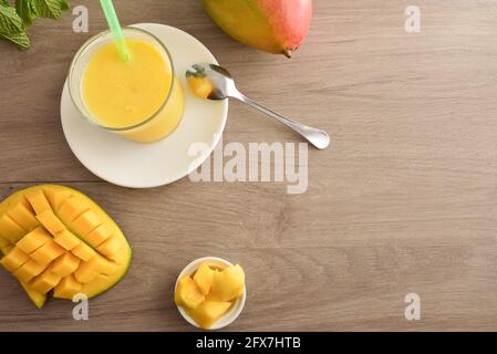 Glass with mango juice served on plate on wooden table with fruit and portions. Top view. Stock Photo