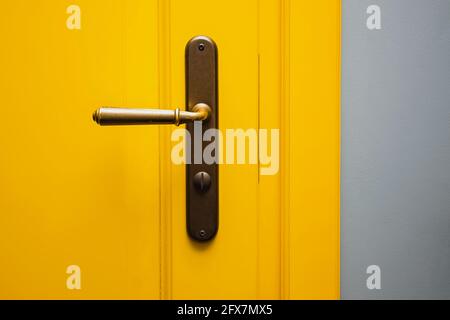 Yellow door with a bronze door handle close-up. Stock Photo