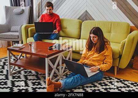 Couple working at home on their laptops in cozy stylish living room Stock Photo
