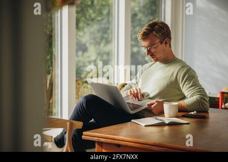 Man sitting at home using laptop. Man searching some information on laptop computer. Stock Photo
