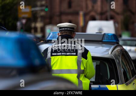 Freiburg, Germany. 05th May, 2021. A police officer is standing between two police emergency vehicles. Credit: Philipp von Ditfurth/dpa/Alamy Live News Stock Photo