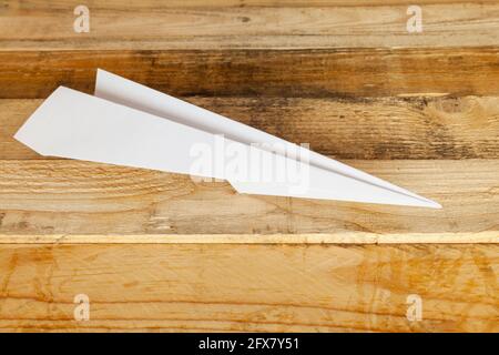 White paper plane on wooden blue background isolated. Stock Photo