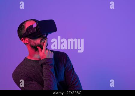 young man using virtual reality headset, experiencing immersion in virtual reality, concentrated while working Stock Photo