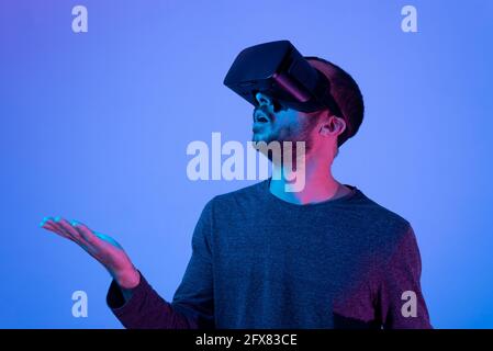 young amazed man working with virtual reality glasses raising hands and touching something, using new and innovative technology at work Stock Photo