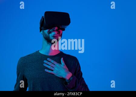 young smiling man working with virtual reality glasses, with surprised and happy expression Stock Photo
