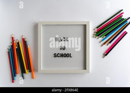 Letterboard with Words That Spell Back To School, with colored pencils on a white background, on a white background, horizontal Stock Photo