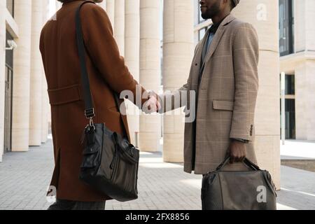 Two young businessmen shaking hands during their meeting in the city Stock Photo