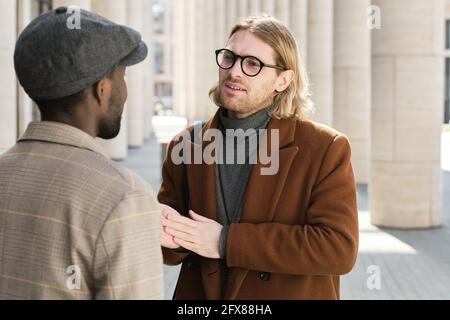 Two colleagues talking to each other while meeting on the street Stock Photo