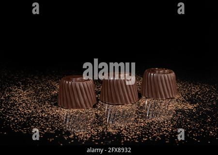 Chocolate candies on a dark background with reflection. Piece by piece and as a whole. Filling of nuts and fruits. Copy space. Stock Photo