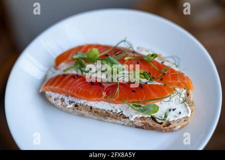 Open sandwich with cereal bread, salmon, cream cheese, microgreens. Close up, selective focus. Concept for healthy nutrition Stock Photo