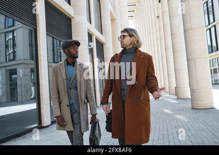 Young people talking and walking along the street in the city in summer day Stock Photo