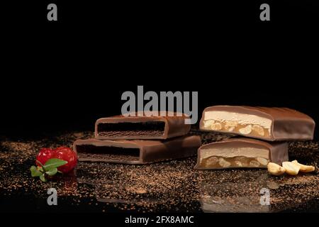 Chocolate candies on a dark background with reflection. Piece by piece and as a whole. Filling of nuts and fruits. Copy space. Stock Photo