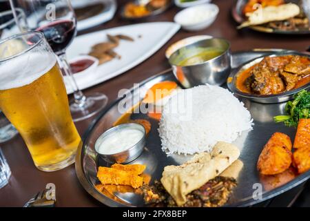 Traditional Nepali thali or dal bhat in restaurant with beer and wine glasses, in Kathmandu, Nepal Stock Photo