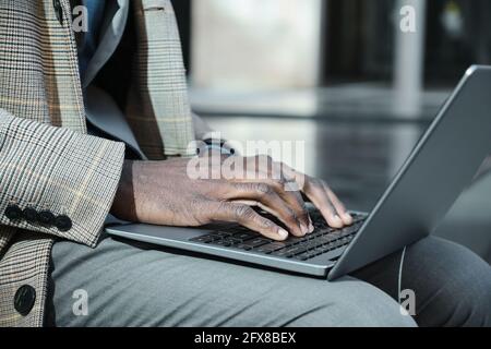 Close-up of African man typing on laptop and working online Stock Photo