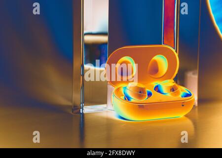 Wireless blue earbuds with a white background with two prisms. Negative edgy filter. Close up Stock Photo